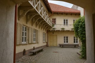 Внутренний двор музея Адама Мицкевича на улице Бернардину с тёплой жёлтой штукатуркой, деревянными ставнями и галереей