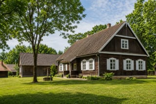 Wooden Lietuvininkai house at Agluonėnai Ethnographic Homestead with a neat yard and farm buildings