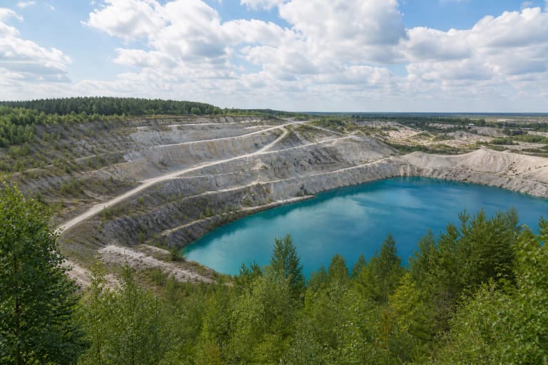 Akmenės karjerų apžvalgos aikštelė su šviesiais klinčių karjero šlaitais, tvenkiniu ir miško juosta