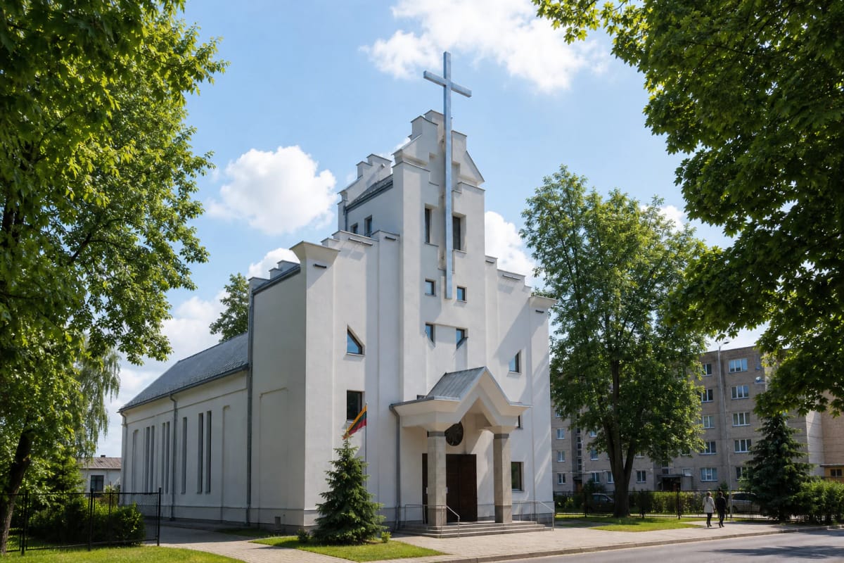 White St Casimir Church in Alytus with a tall square tower, an exceptionally high metal cross, and an angular entrance canopy