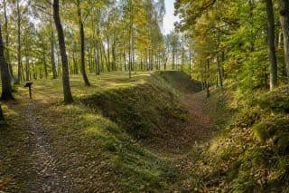 Wooded summit, defensive rampart, and leaf-covered ditch at Anduliai Hillfort