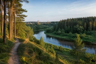 A bend of the Šventoji River near Anykščiai, with pine forest, a footpath, and distant church spires