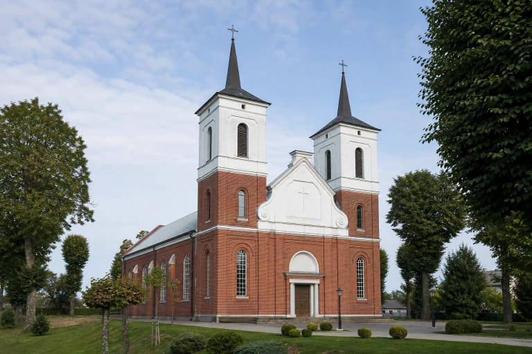 The red-brick façade of the Church of St Michael the Archangel in Ariogala with white upper stages and spires on its twin towers