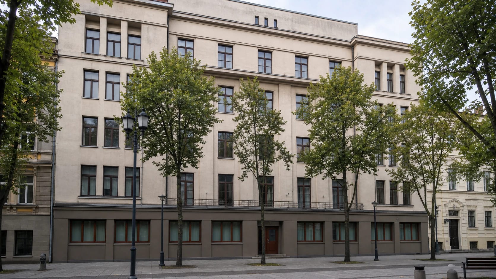 Light five-storey facade of the Ateitininkai Union Palace in Kaunas on Laisvės aleja with rectangular windows, shallow projections, and trees