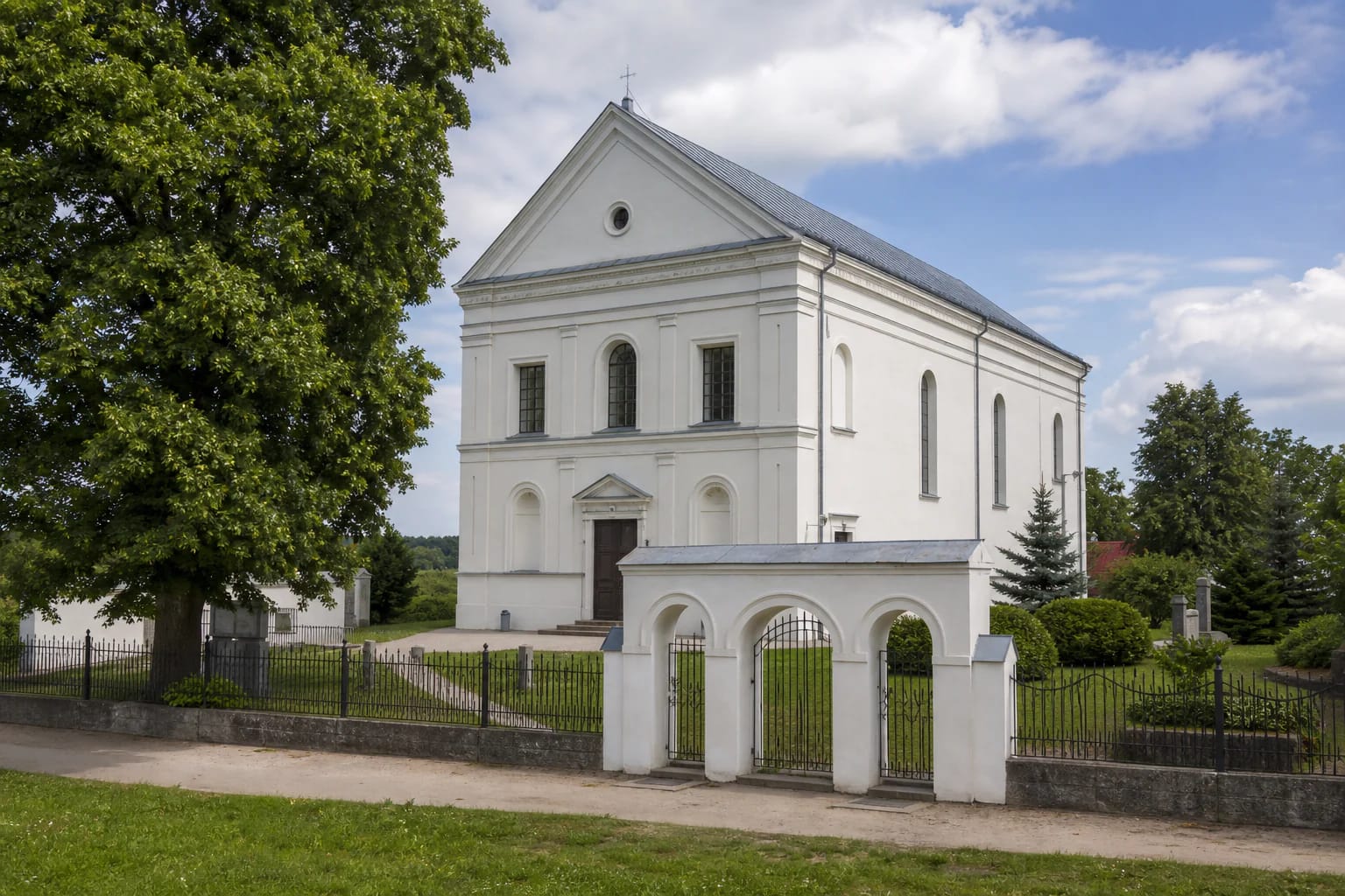 Towerless pale Aukštoji Panemunė Church of the Holy Name with a high triangular pediment and masonry gate