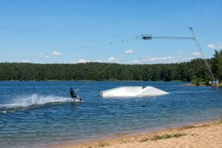 Wakeboarder on a cable course above Elektrėnai Reservoir beside a white obstacle