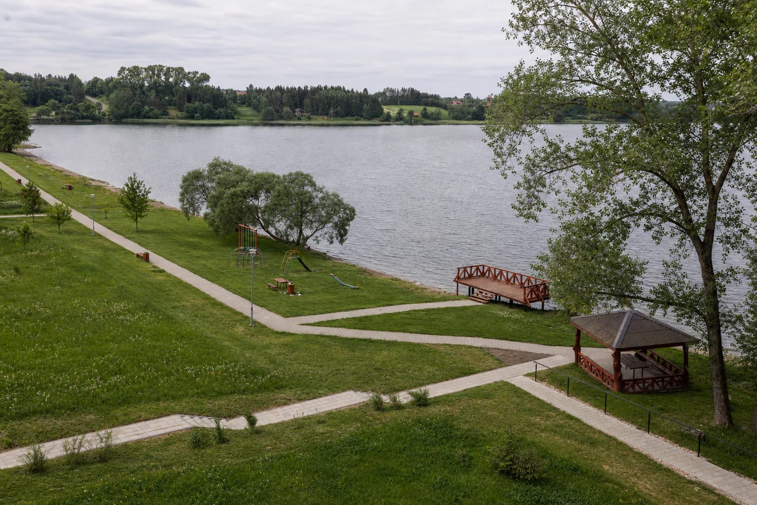 Balninkų paplūdimio žolėta pakrantė su takais, vaikų aikštele, terasa ir medine pavėsine prie Alaušų ežero
