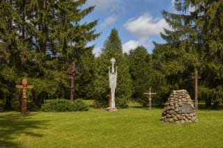 Baltijos kelio kryžių slėnio veja su lauko riedulių Laisvės aukuru ir tarp eglių išdėstytais skirtingais kryžiais