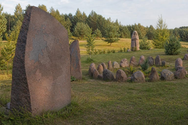 Baltų sodo akmens paminklai su baltų genčių žemėlapiu žalioje Avilčių sodybos pievoje