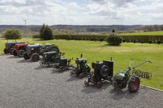 Vintage tractors and wheeled stationary engines arranged in the outdoor display at Biliūnai Traditional Crafts Centre