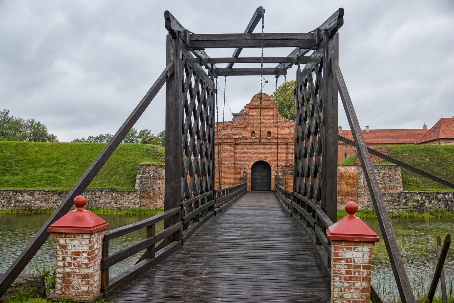 Wooden Biržai Castle Bridge crossing the moat towards the fortress's red-brick gateway