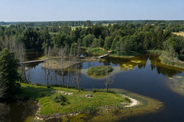 Biržai Regional Park's karst-lake mosaic with reed islets, woodland, and a wooden boardwalk