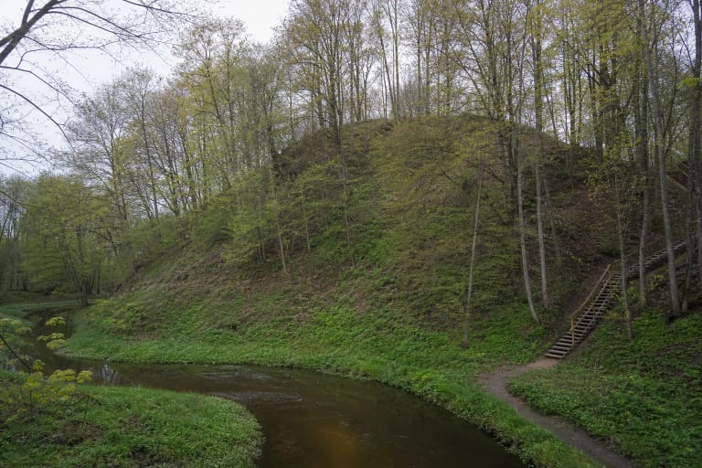 Mišku apaugęs status Burbaičių piliakalnis virš Kražantės upės, mediniai laiptai ir žalias slėnis