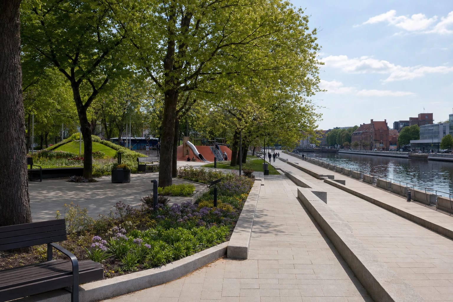 Pale-stone terraces, green trees, paths, and the River Danė at Danė Riverside Square in central Klaipėda