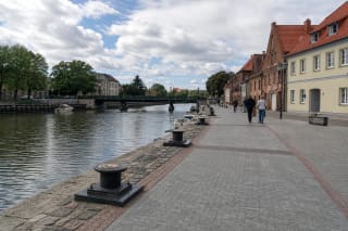 Grey-paved Buriuotojų quay with memorial bollards beside the River Danė in central Klaipėda