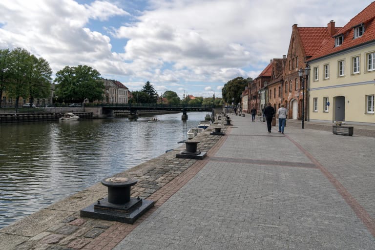 Pilkomis trinkelėmis grįsta Buriuotojų krantinė su paminkliniais knechtais prie Danės upės Klaipėdos centre