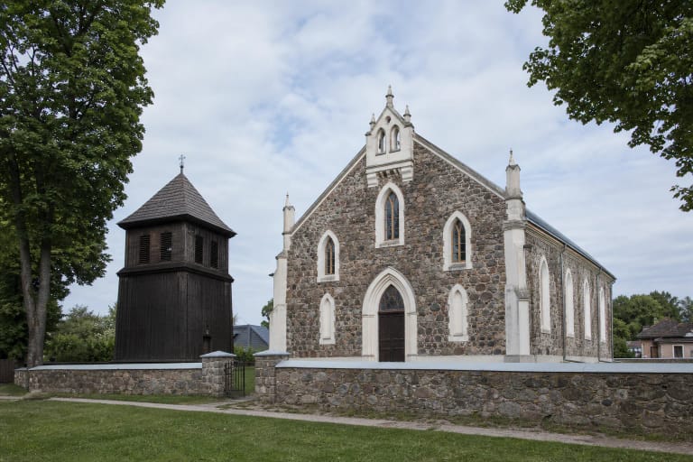 Daugų Dievo Apvaizdos bažnyčia iš lauko akmens mūro ir atskira medinė varpinė žaliame šventoriuje