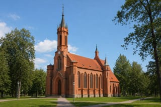Краснокирпичный неоготический фасад костёла Шкаплерной Божией Матери в Друскининкае с высокой башней, часами и стрельчатым входом
