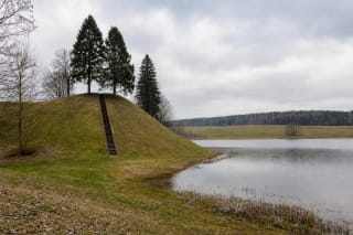 Grass-covered Dukurnonys Hillfort with timber stairs beside Lake Surmius
