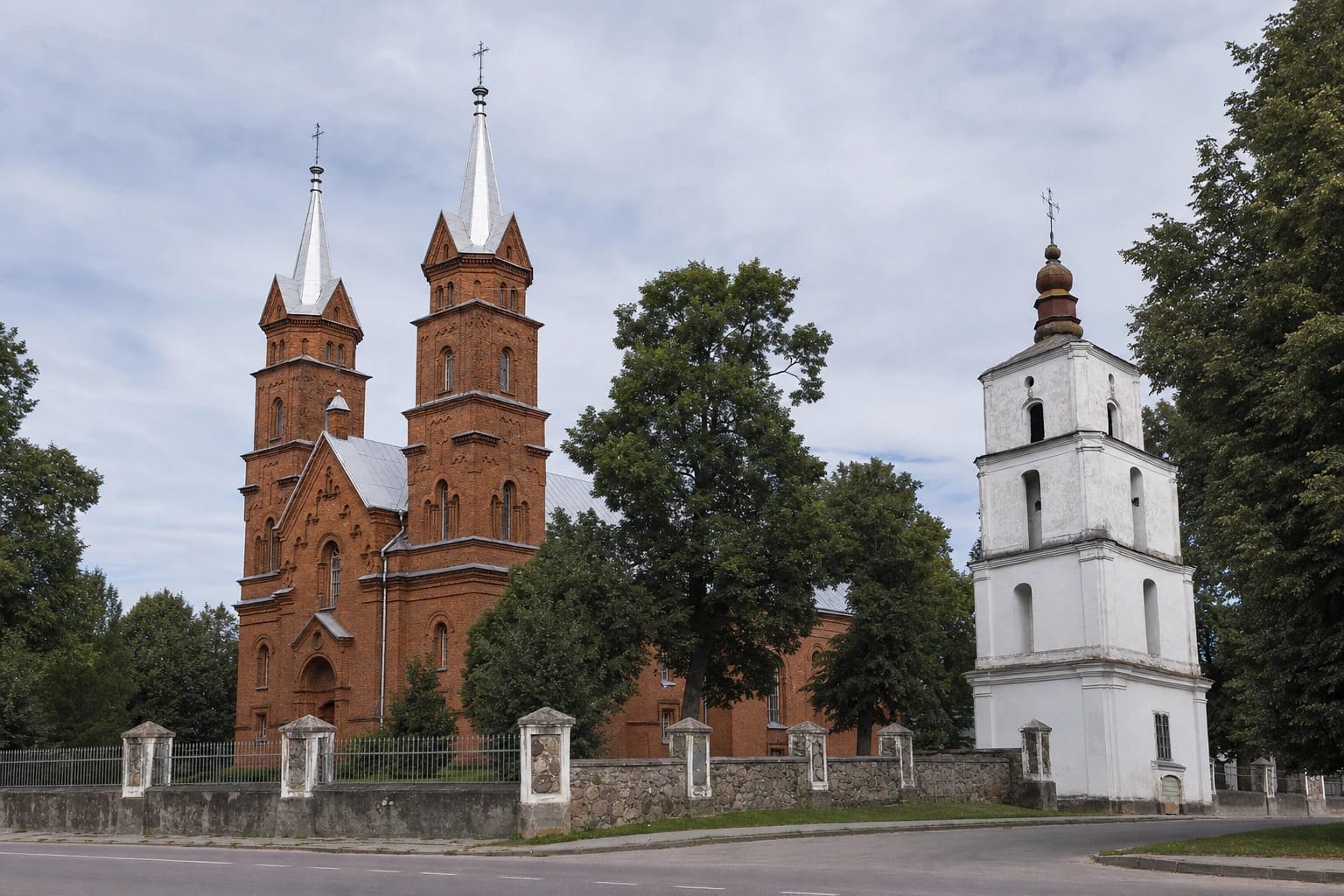 Dusetos Holy Trinity Church in red brick with two tall towers and a separate white eighteenth-century bell tower among trees