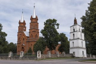 Церковь Пресвятой Троицы в Дусетосе из красного кирпича с двумя высокими башнями и отдельной белой колокольней XVIII века среди деревьев