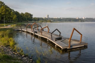 Angular deck of Elektrėnai Pontoon Pier with rust-coloured arches and a net lounger above the calm reservoir
