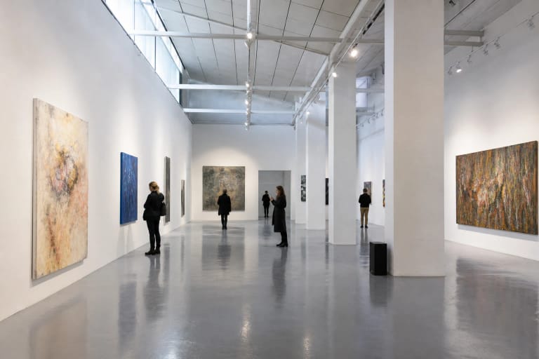 Galerijos CECHAS VILNIUS balta aukšta salė su šiuolaikinio meno paveikslais ir lankytojais