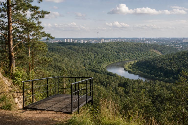 Gariūnų regyklos metalinė platforma virš miškingo Neries slėnio su TV bokštu horizonte