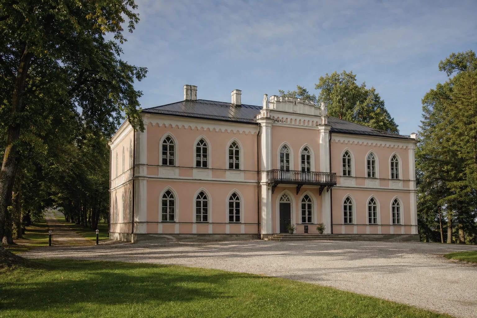 Light restored Glitiškės Manor palace with pointed-arch windows, balcony, and a park avenue