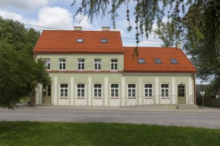 Long pale-green facade and red tiled roof of Gražutė Regional Park Visitor Centre, with its access ramp in Salakas