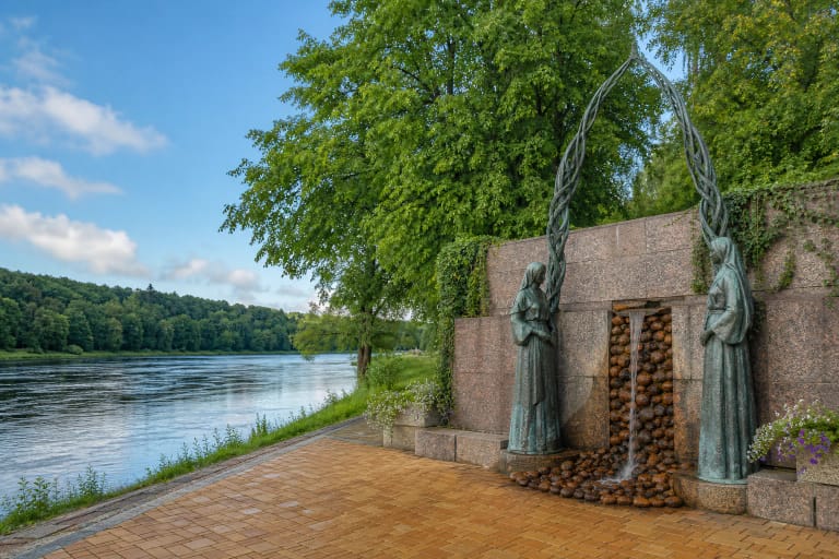 Бронзовые речные духи обрамляют текущую по камням минеральную воду у источника Грожис на набережной Немана в Друскининкае