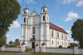 Белая двухбашенная барочная церковь Святого архангела Михаила и Иоанна Крестителя в Езнасе с волнистым фронтоном и красной жестяной крышей