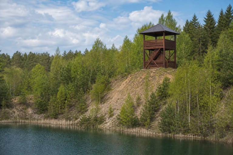 Jogaudų apžvalgos bokštas ant buvusio karjero šlaito virš melsvai žalio tvenkinio ir jaunų pušų