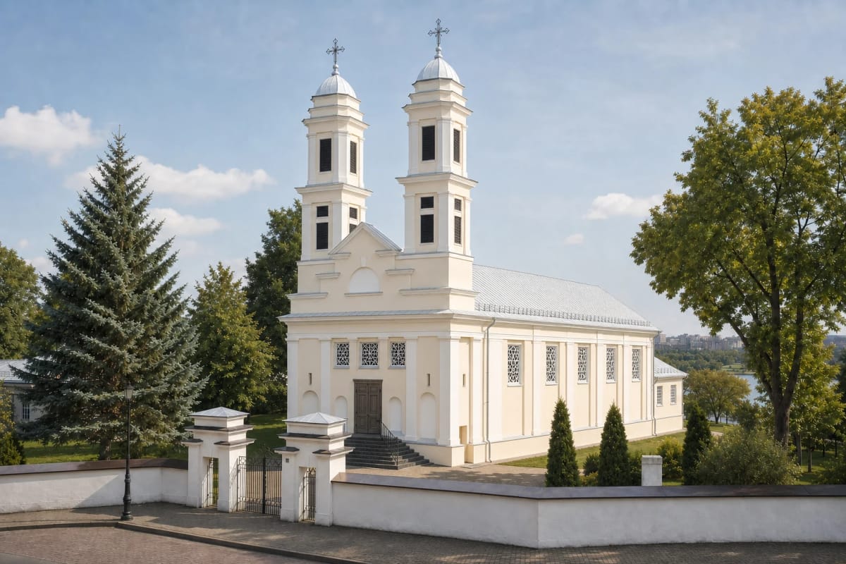 Светлый фасад двухбашенной церкви Святого апостола Иакова в Йонаве и ворота погоста в летний день