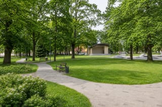 Green Joniškis City Park with a curving path, summer stage and youth recreation area