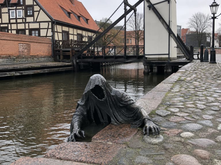 Bronze Black Ghost sculpture by the Klaipėda castle moat and swing bridge