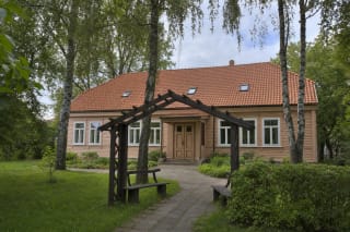 Šviesus medinis Juozo Grušo namas su raudonų čerpių stogu, sodo beržais ir arkine pergole prie įėjimo Žaliakalnyje