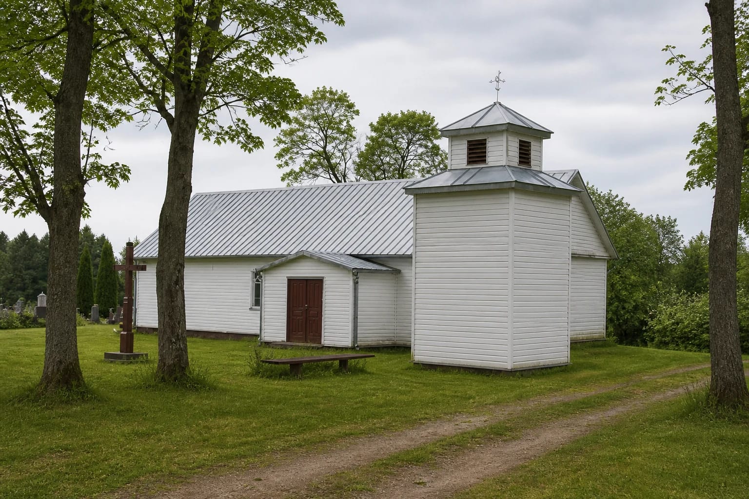 White wooden Kalnujai Church of St Victor with a small bell turret among trees
