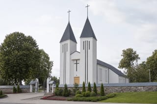 White twin-towered Kaltinėnai Church of St John the Baptist behind a stone wall