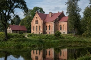 Red-brick Kamariškiai Manor beside a park pond in Zarasai District