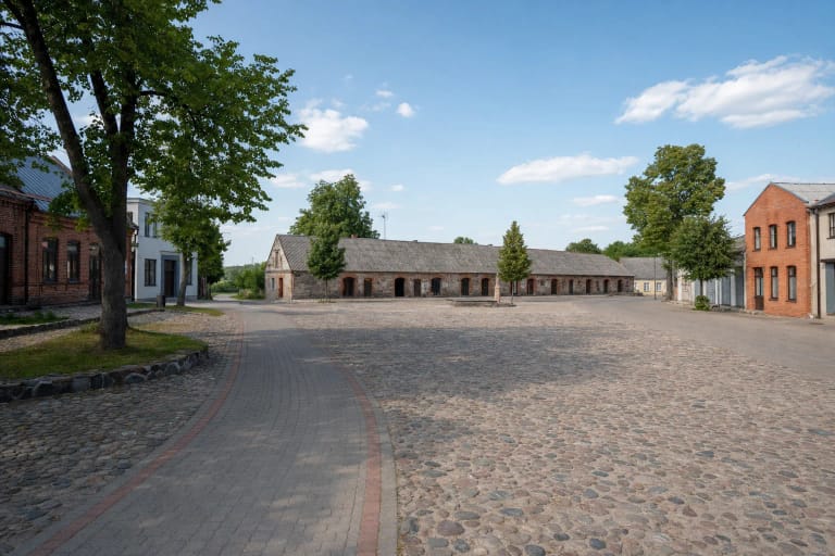 Akmenimis grįsta Katyčių turgaus aikštė tarp žemų istorinių mūrinių pastatų