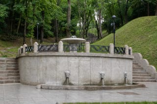Restauruotas apatinis Kauko laiptų fontanas su trimis jaučių galvų vandens snapais, lenkta granito siena ir į miškingą Žaliakalnio šlaitą kylančiais laiptais
