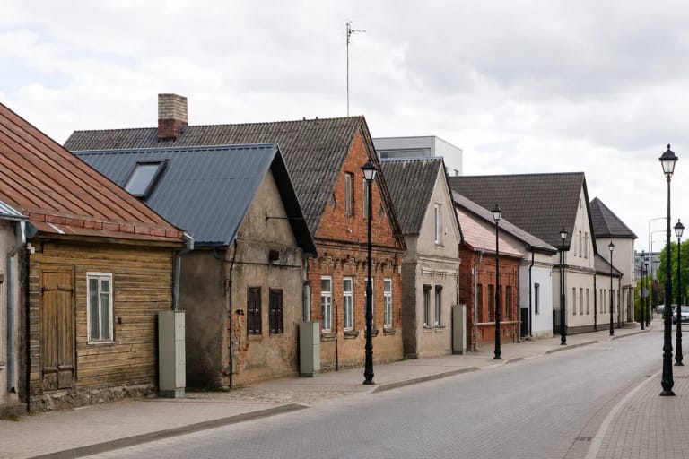 Kauno gatvės Jonavoje perspektyva su kukliais vieno ir dviejų aukštų raudonų plytų, tinkuotais ir mediniais namais