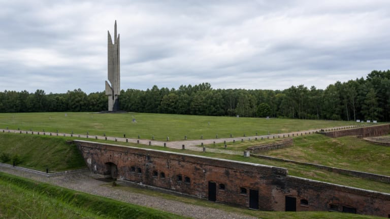 Kauno IX forto memorialo laukas su žemais forto pylimais ir aukštu betoniniu paminklu