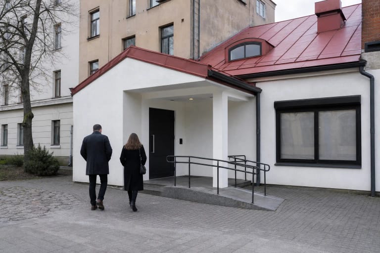 Nedidelis baltas Kauno miesto kamerinio teatro įėjimas Kęstučio gatvės kieme su raudonu stogu ir rampa