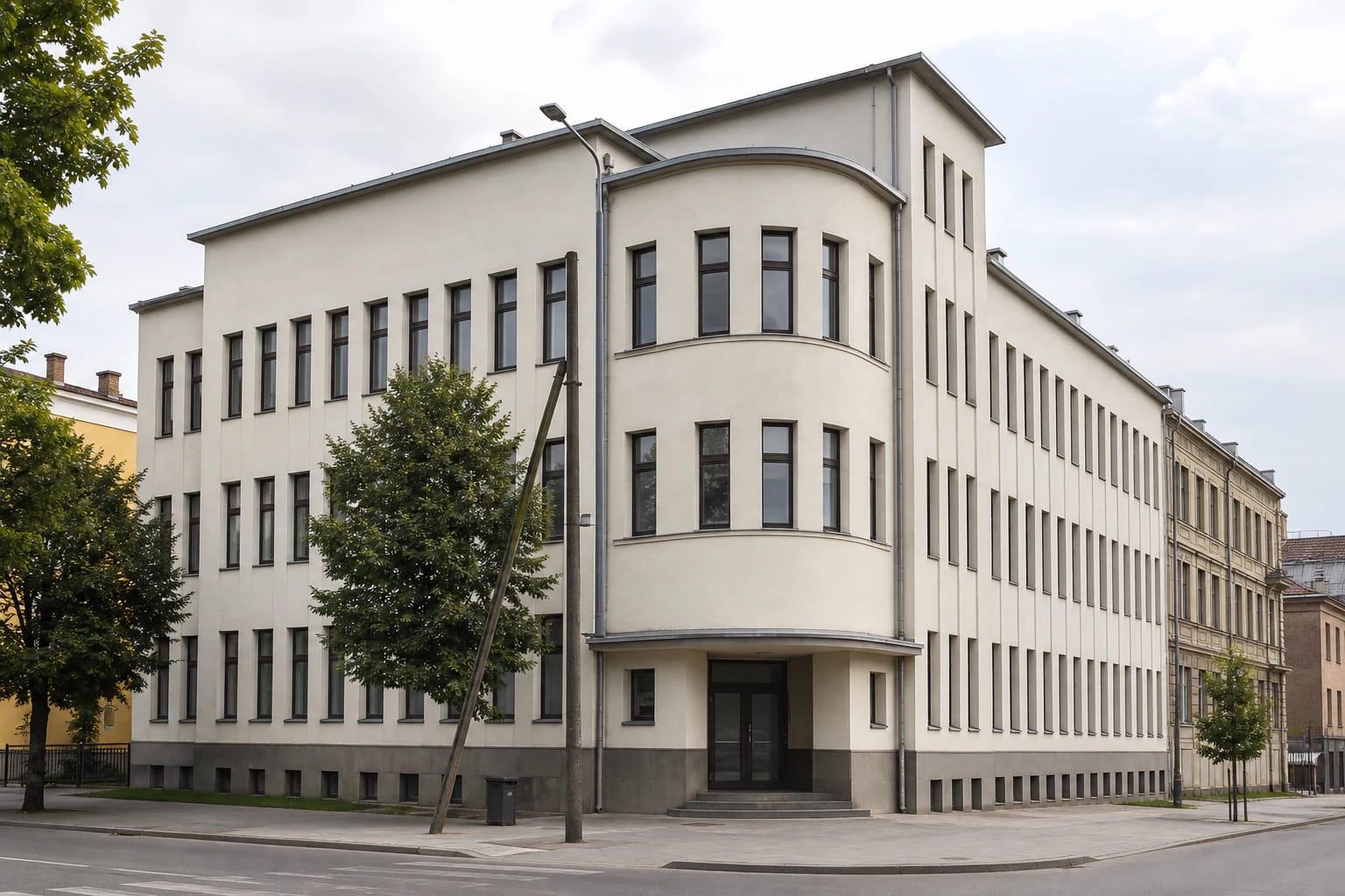 Modernist corner facade of the Kaunas City Sickness Fund Palace with curved volume, vertical window rows, and modest entrance canopy