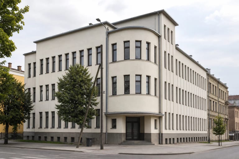 Kauno miesto ligonių kasų rūmų modernistinis kampinis fasadas su lenktu tūriu, vertikaliomis langų eilėmis ir kukliu įėjimo stogeliu