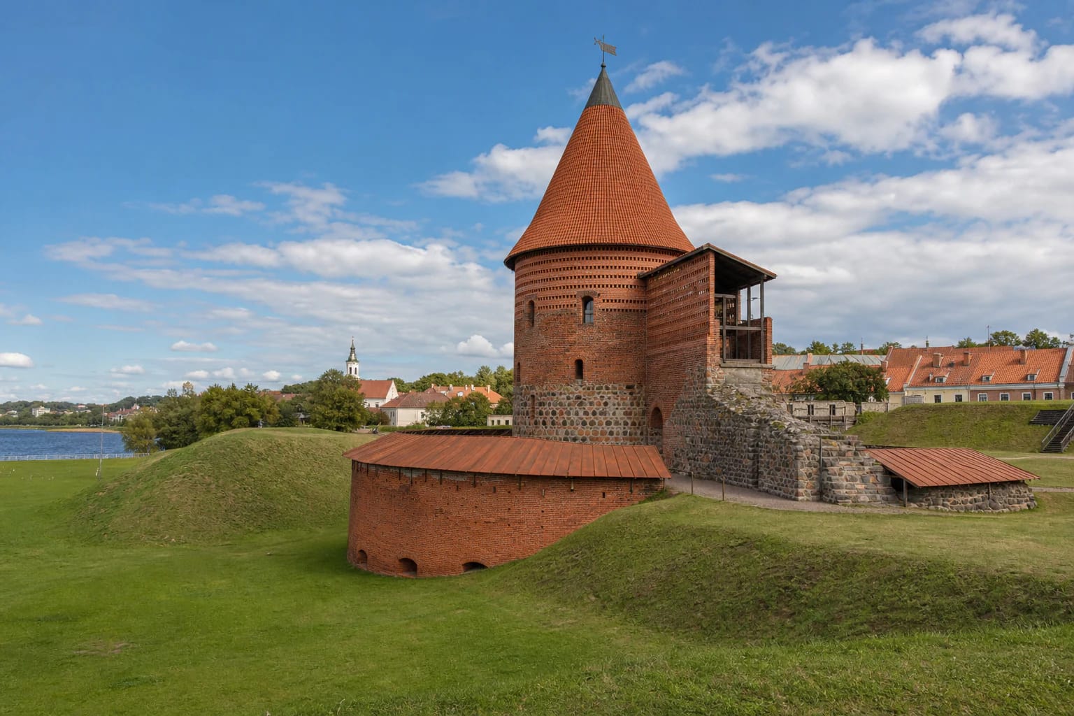 Round red-brick tower and bastion of Kaunas Castle on green defensive slopes