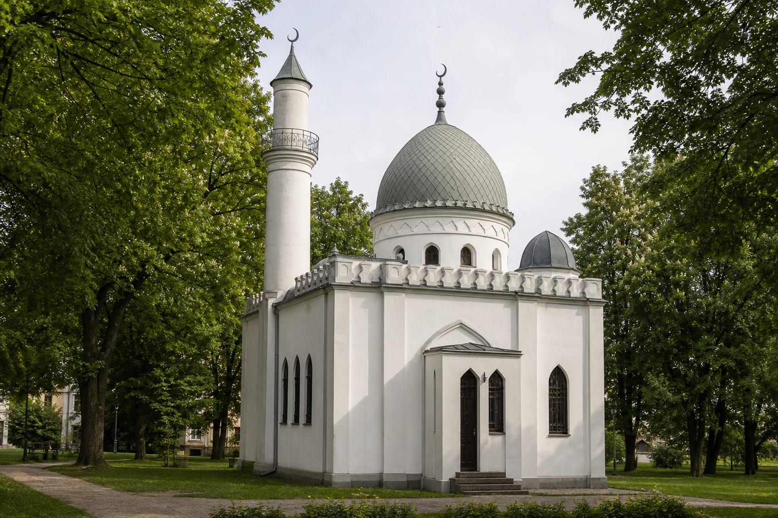 White Kaunas Tatar Mosque in Ramybes Park with central dome, one minaret, arched windows, and tree-framed facade