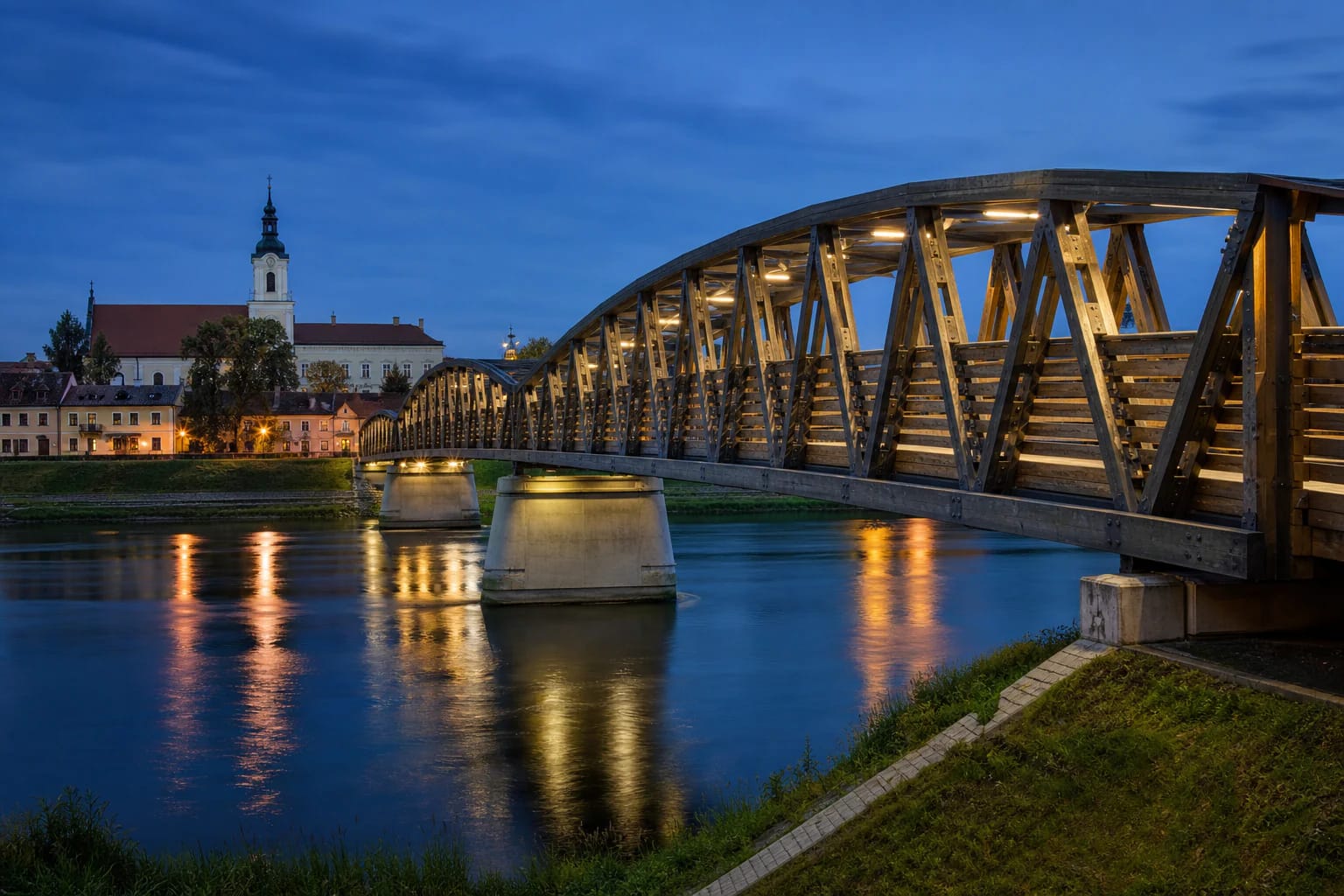 Kėdainiai pedestrian bridge over the Nevėžis at blue hour with the historic riverbank beyond